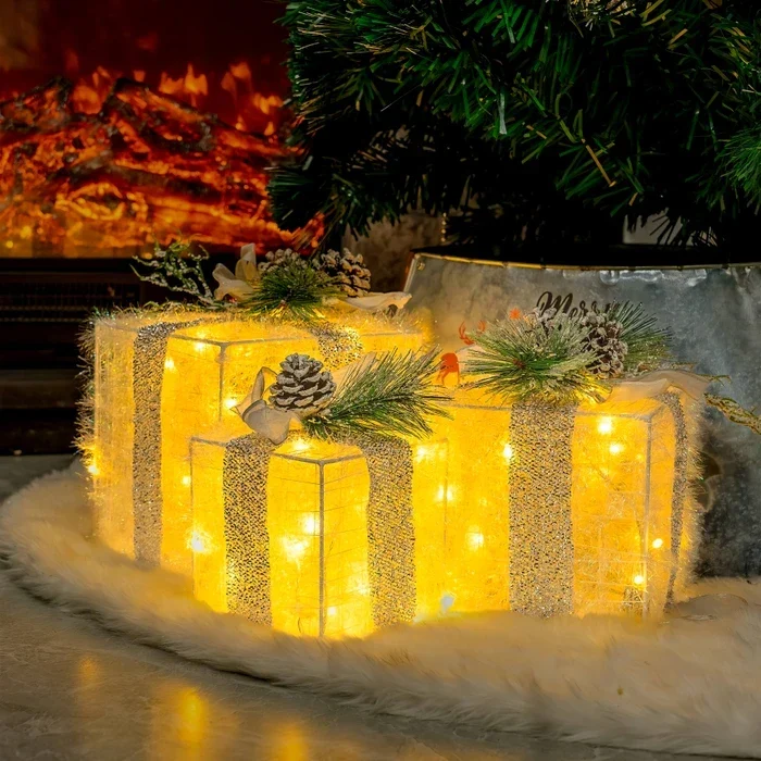Kerstdecoratie – verlichte cadeaudozen met dennenappels en berijpt groen